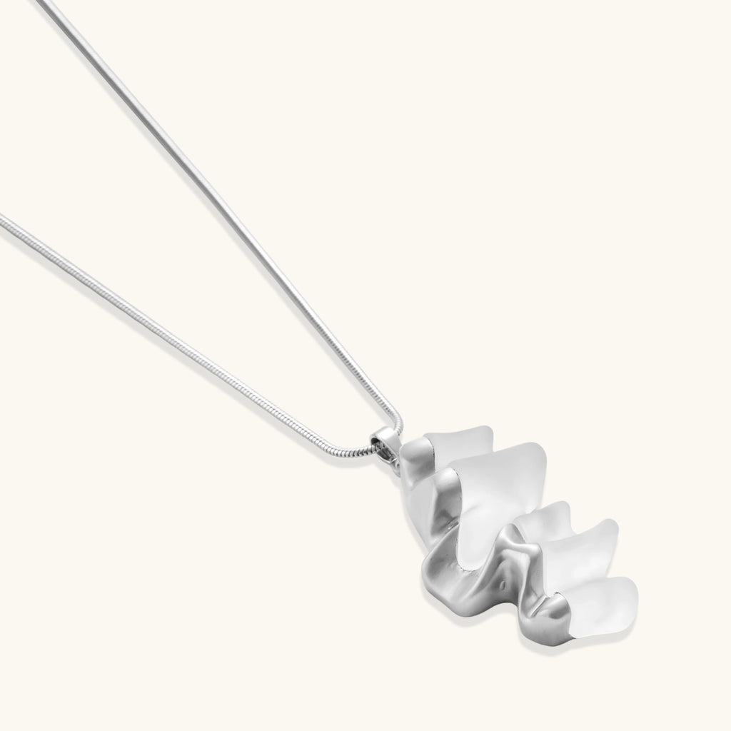 Close-up of a sculptural necklace with flowing wave pendant made from eco-zinc alloy on adjustable chain