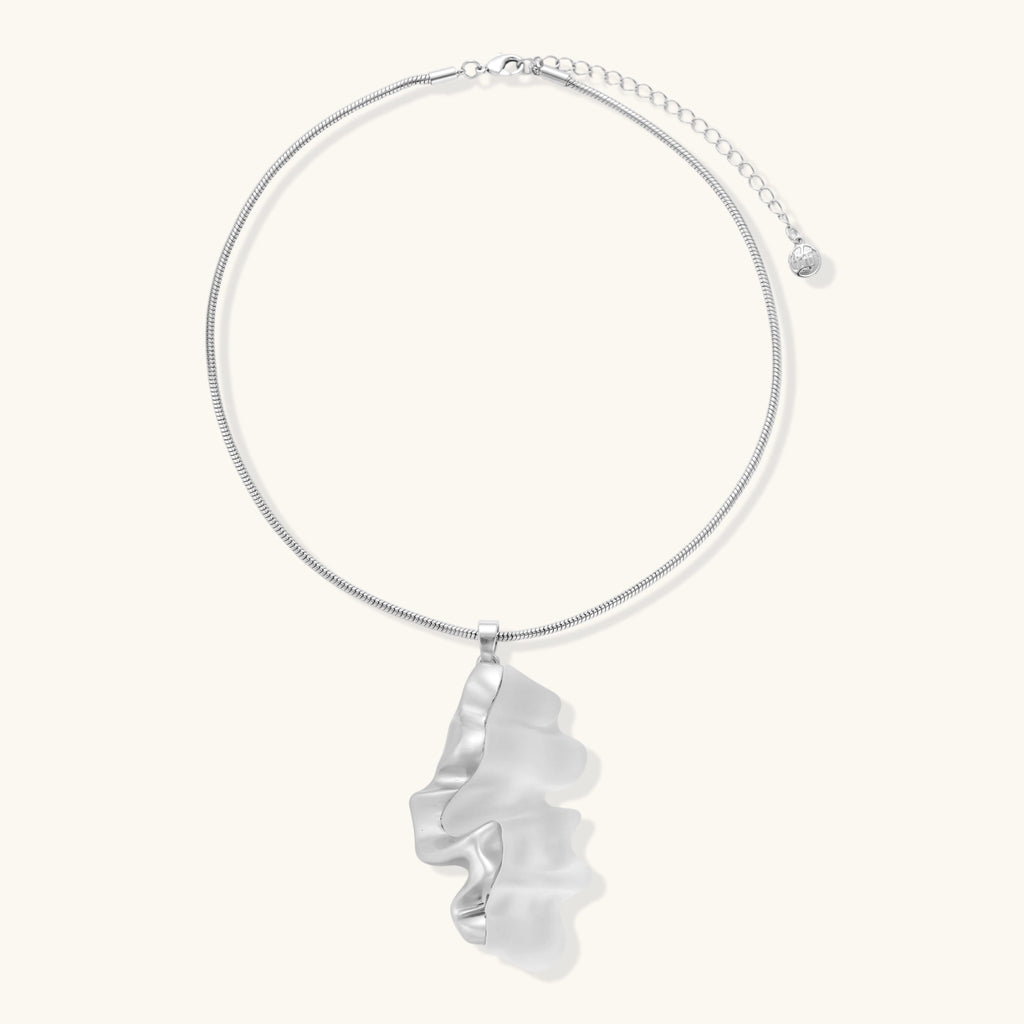 Close-up of a sculptural necklace with flowing wave pendant made from eco-zinc alloy on adjustable chain