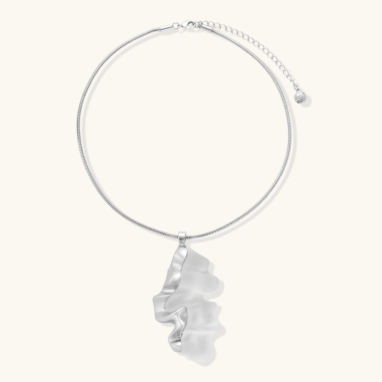 Close-up of a sculptural necklace with flowing wave pendant made from eco-zinc alloy on adjustable chain