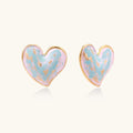 Heart-shaped stud earrings with swirled turquoise and pink enamel in gold-plated frames on cream background