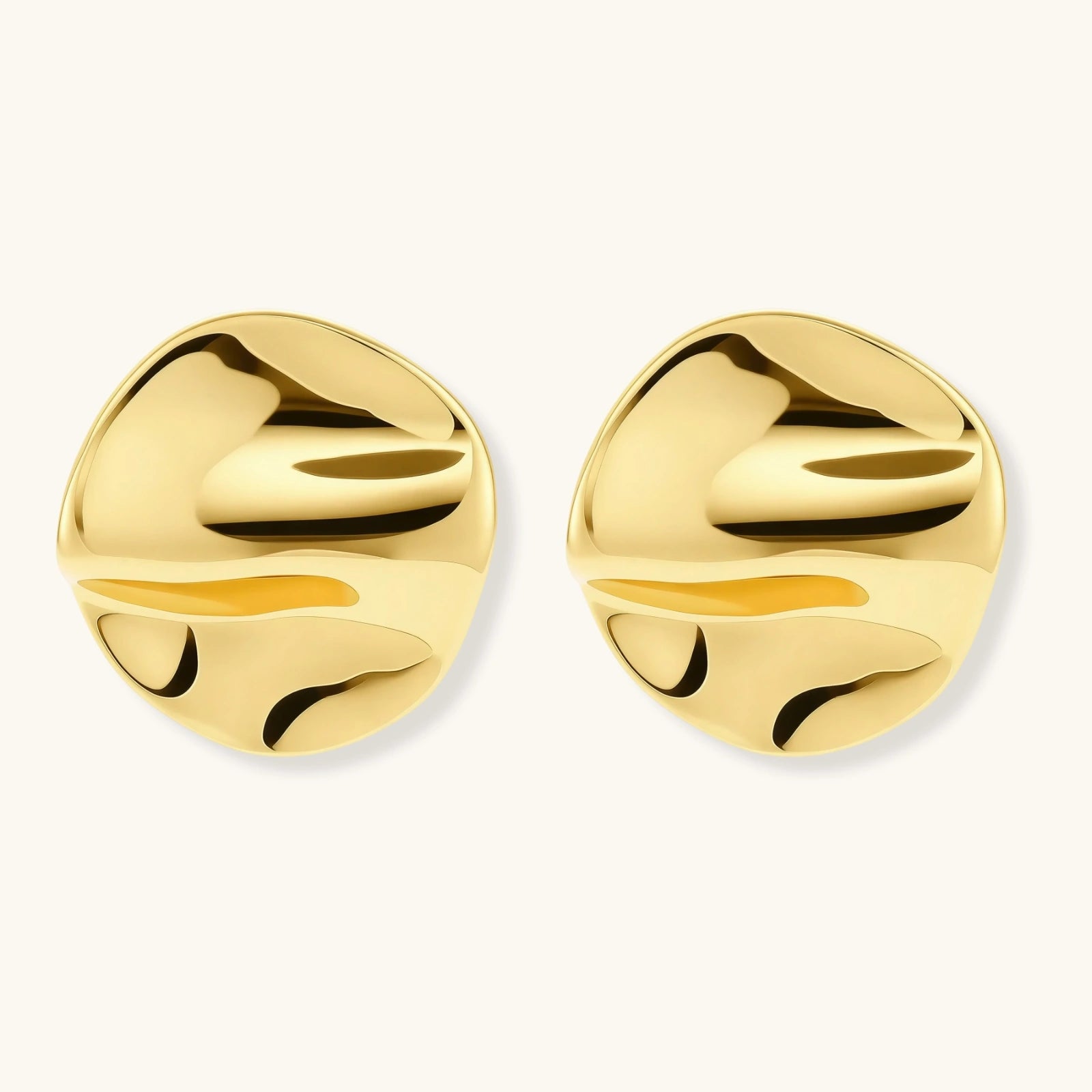 Close-up of organic gold-plated sterling silver stud earrings with flowing sculptural design and curved cut-outs