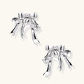 Sculptural bow earrings in polished white gold plate with sparkling zirconia stones and flowing ribbon details