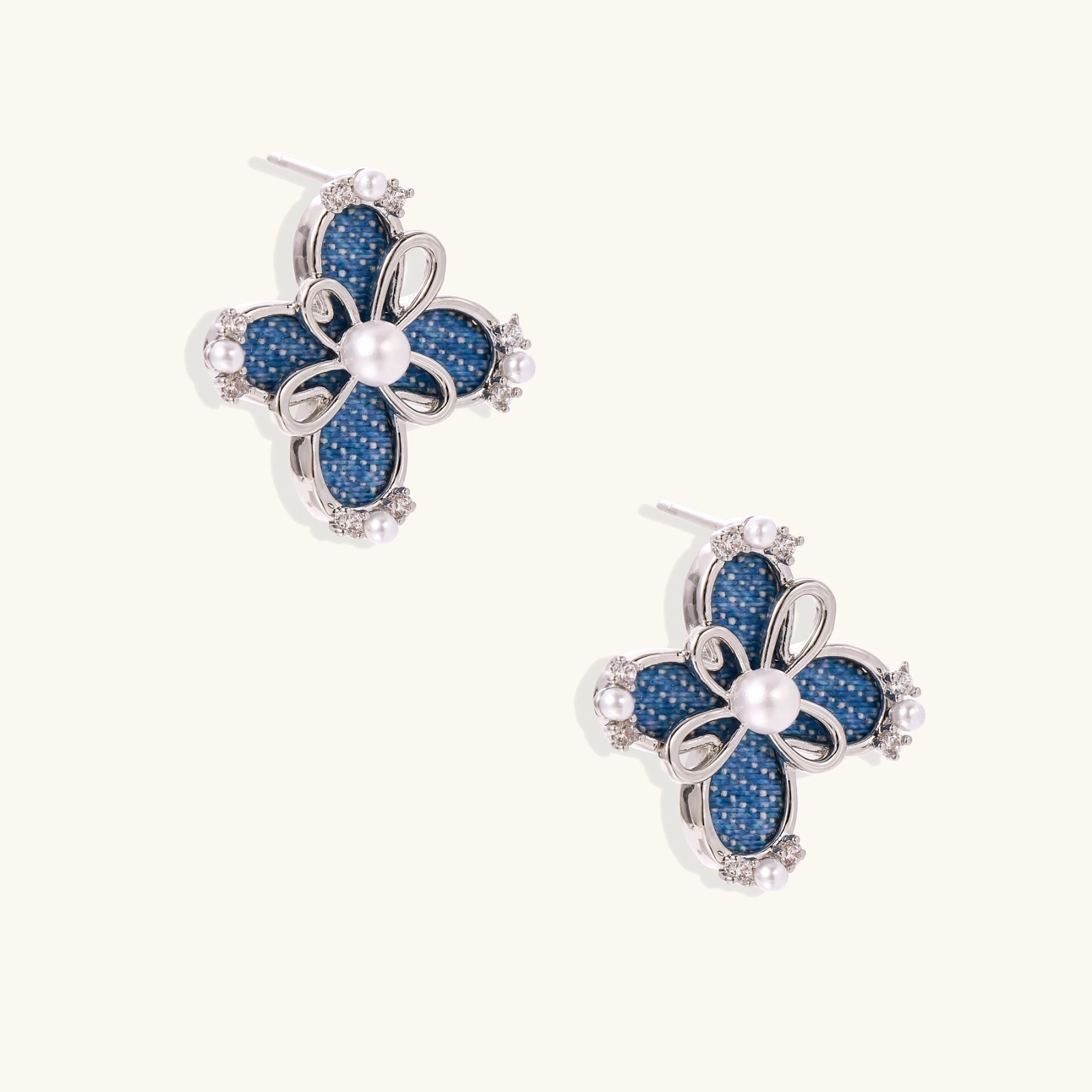 Blue denim fabric flower studs with white gold plated petals, pearl center, and zirconia accents on white background